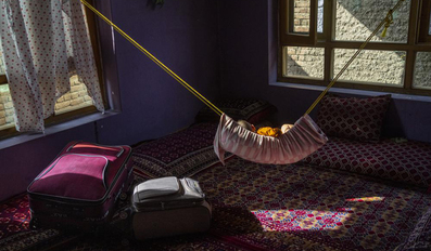 A child sleeps on a hammock next to packed suitcases